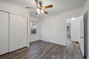 Unfurnished bedroom with a closet, dark wood-style floors, and a ceiling fan