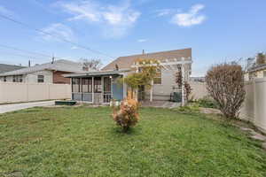 Rear view of house with a fenced backyard, a sunroom, roof with shingles, and a patio
