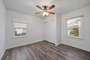 Unfurnished bedroom with dark wood finished floors, a ceiling fan, a closet, and multiple windows