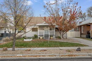 View of front of home with a porch, roof with shingles, driveway, and a gate