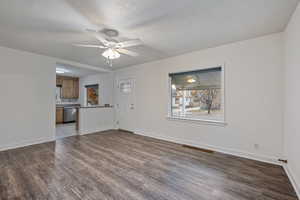 Unfurnished living room with dark wood-type flooring, a textured ceiling, and a ceiling fan