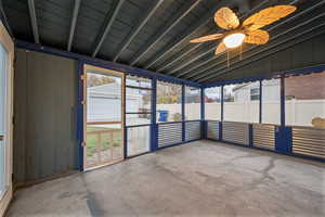 Unfurnished sunroom with ceiling fan, vaulted ceiling, and healthy amount of natural light