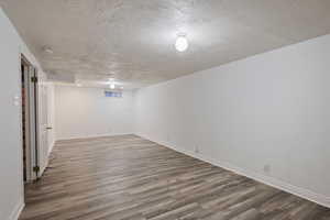 Finished below grade area with a textured ceiling and light wood finished floors