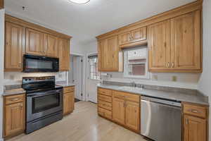 Kitchen with stainless steel appliances, light wood-style floors, a textured ceiling, brown cabinets, and light countertops