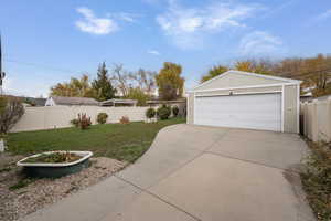 Fenced backyard featuring a detached garage and an outbuilding