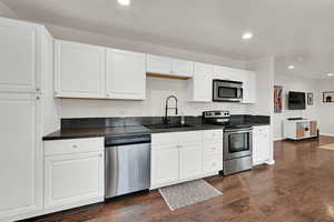 Kitchen with white cabinetry, stainless steel appliances, recessed lighting, and dark wood finished floors