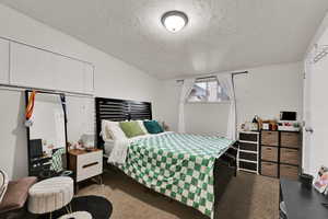 Bedroom with a textured ceiling and dark colored carpet