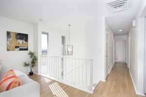 Hall with an upstairs landing, light wood-type flooring, and a chandelier