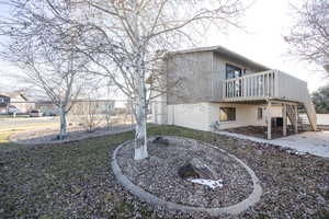 View of property exterior with brick siding, stairway, a wooden deck, and a patio area