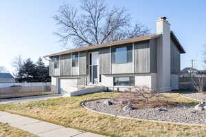 Bi-level home with brick siding, a chimney, concrete driveway, a garage, and a shingled roof