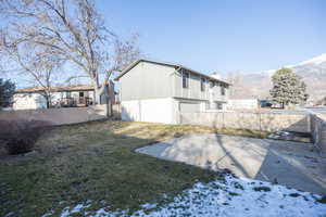Rear view of house featuring a fenced backyard, brick siding, a chimney, and a mountain view