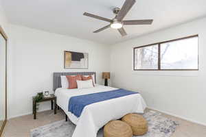 Carpeted bedroom with a closet and a ceiling fan