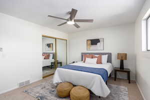 Carpeted bedroom with a ceiling fan and a closet
