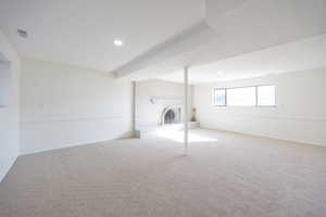 Below grade area featuring a brick fireplace, carpet, and recessed lighting