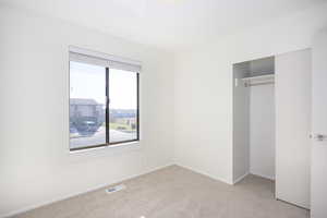 Unfurnished bedroom featuring a closet and light carpet