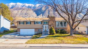 Bi-level home with a mountain view, concrete driveway, brick siding, and a garage