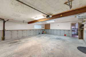 Garage with a garage door opener. Extra wide and deep with back door leading into workshop