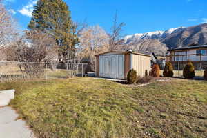 Fenced backyard featuring a mountain view and a storage shed