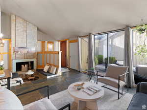 Living area with stone tile floors, lofted ceiling, a brick fireplace, and expansive windows