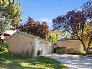 View of side of home with brick siding, a garage, and a lawn