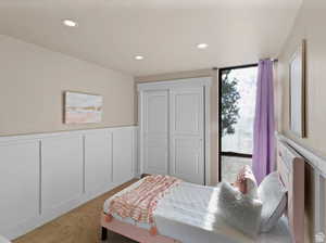 Carpeted bedroom featuring a decorative wall, wainscoting, recessed lighting, and a closet