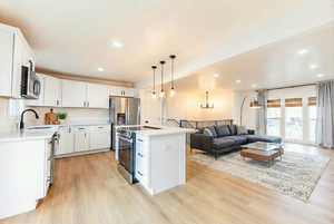 Kitchen with white cabinets, stainless steel appliances, a kitchen island, light wood-style floors, and recessed lighting
