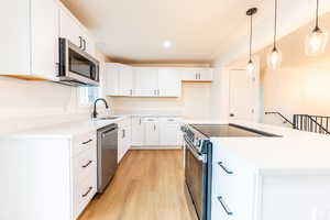 Kitchen featuring white cabinets, stainless steel appliances, hanging light fixtures, and recessed lighting
