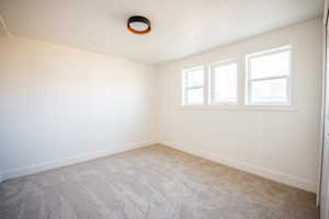 Spare room featuring light colored carpet and a textured ceiling