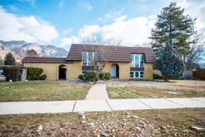 View of property featuring mansard roof, brick siding, and a mountain view