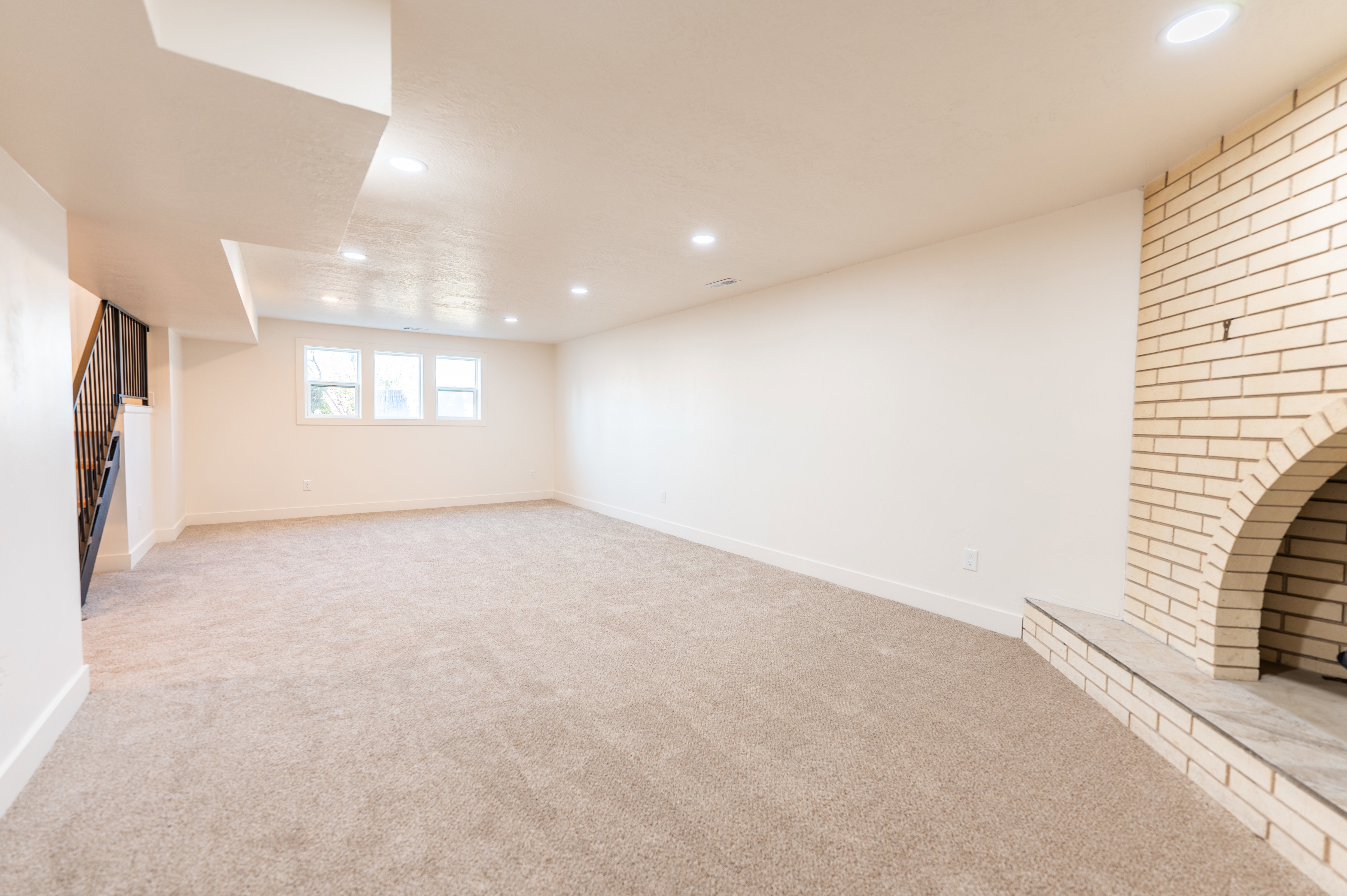 Unfurnished living room featuring light colored carpet, recessed lighting, and stairway