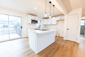 Kitchen featuring hanging light fixtures, white cabinets, a center island, light wood-style floors, and recessed lighting