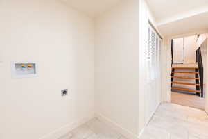 Washroom with electric dryer hookup, washer hookup, and light tile patterned flooring