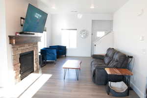 Living room featuring a fireplace, light wood laminate floors, and recessed lighting