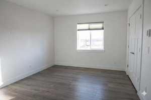 Unfurnished bedroom with baseboards and dark wood finished floors