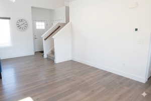 Unfurnished living room with stairway and dark wood-style floors