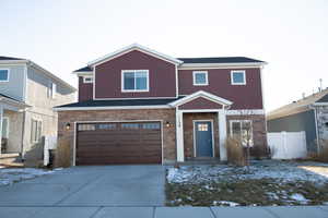 View of front of home with stone siding, driveway, and a garage