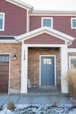 Snow covered property entrance with stone siding