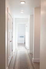 Corridor featuring light wood laminate flooring and a textured ceiling leading to bedroom 2