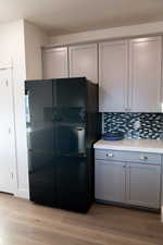 Kitchen with gray cabinets, backsplash, and light wood laminate  flooring