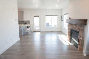 Unfurnished living room featuring a stone fireplace, dark wood-style floors, and recessed lighting