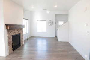 Unfurnished living room featuring wood finished floors and a stone fireplace