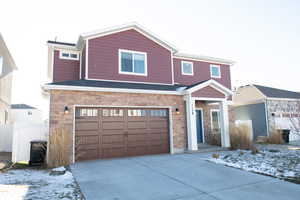 View of front of home featuring stone siding, a garage, and concrete driveway