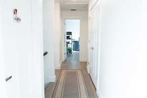 Hall with wood-style floors and attic access. View of the linen closet.