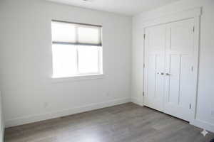 Unfurnished bedroom with wood finished floors and a closet
