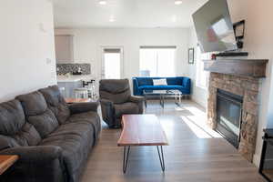 Living room with a fireplace, wood laminate floors, and recessed lighting