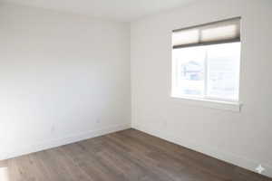 Spare room with dark wood-style flooring and baseboards