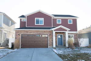 View of front facade with stone siding, driveway, and a garage