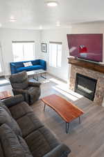 Living area with a stone fireplace, a textured ceiling, and wood laminate floors