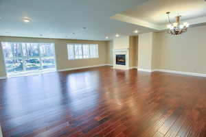 Unfurnished living room featuring a tile fireplace, recessed lighting, dark wood-style floors, and a chandelier