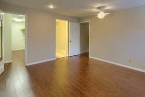 Empty room with dark wood-style flooring and ceiling fan